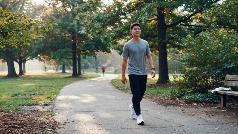 Person walking outdoors in a green park to improve mental and physical health